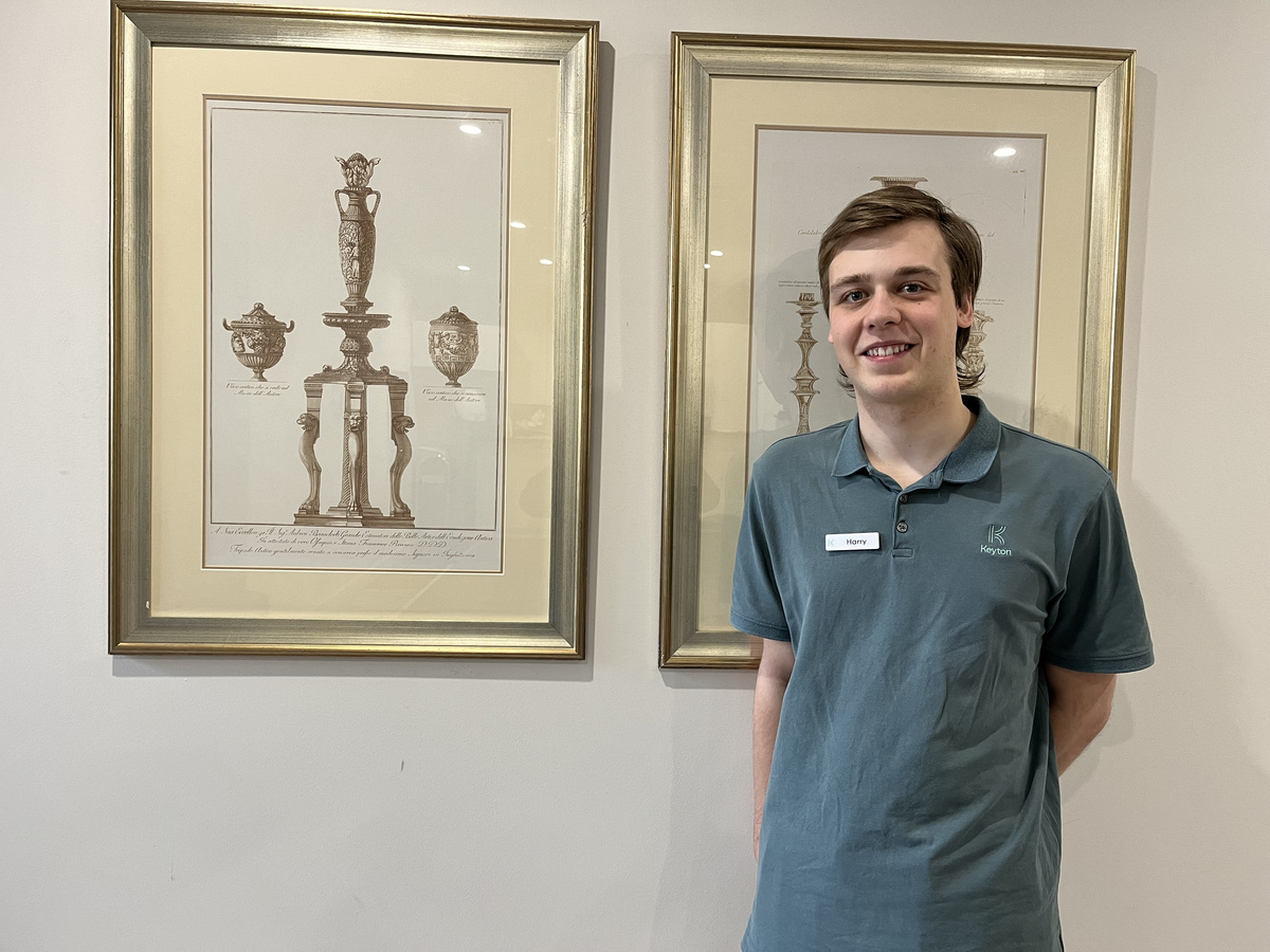 Village support office Harry standing next to some artwork at Menzies Malvern