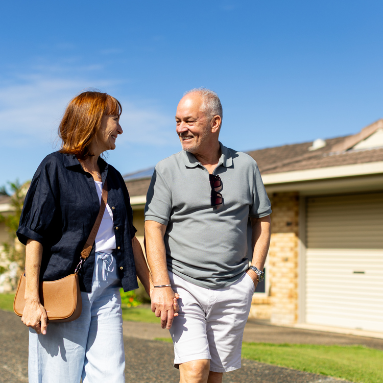 A retired couple holding hands and walking through a retirement village