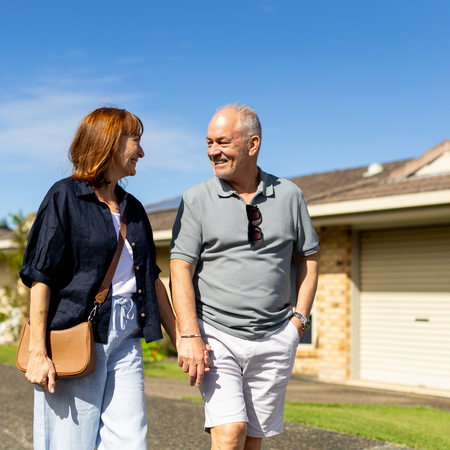 A retired couple holding hands and walking through a retirement village