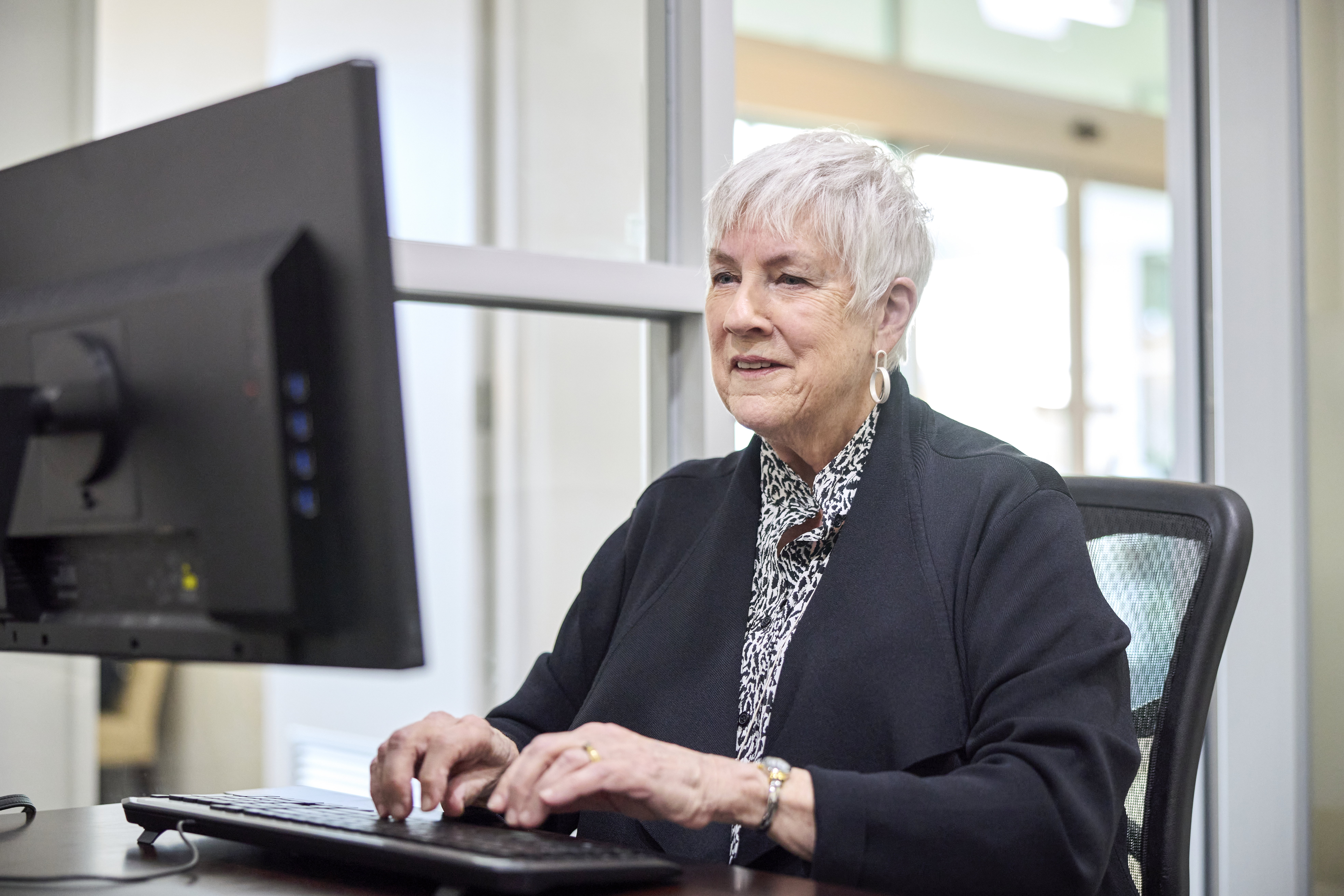a senior using a monitor and a laptop