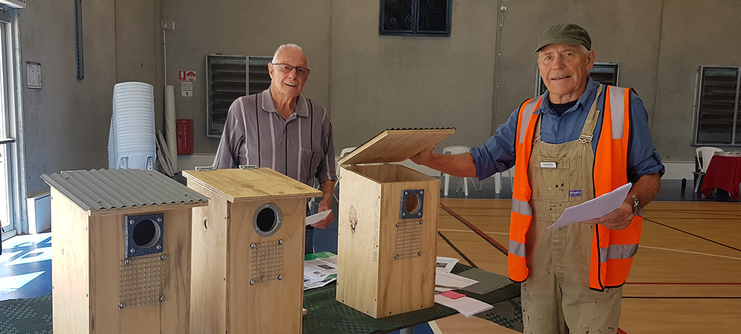 Two senior men standing with homemade bird boxes