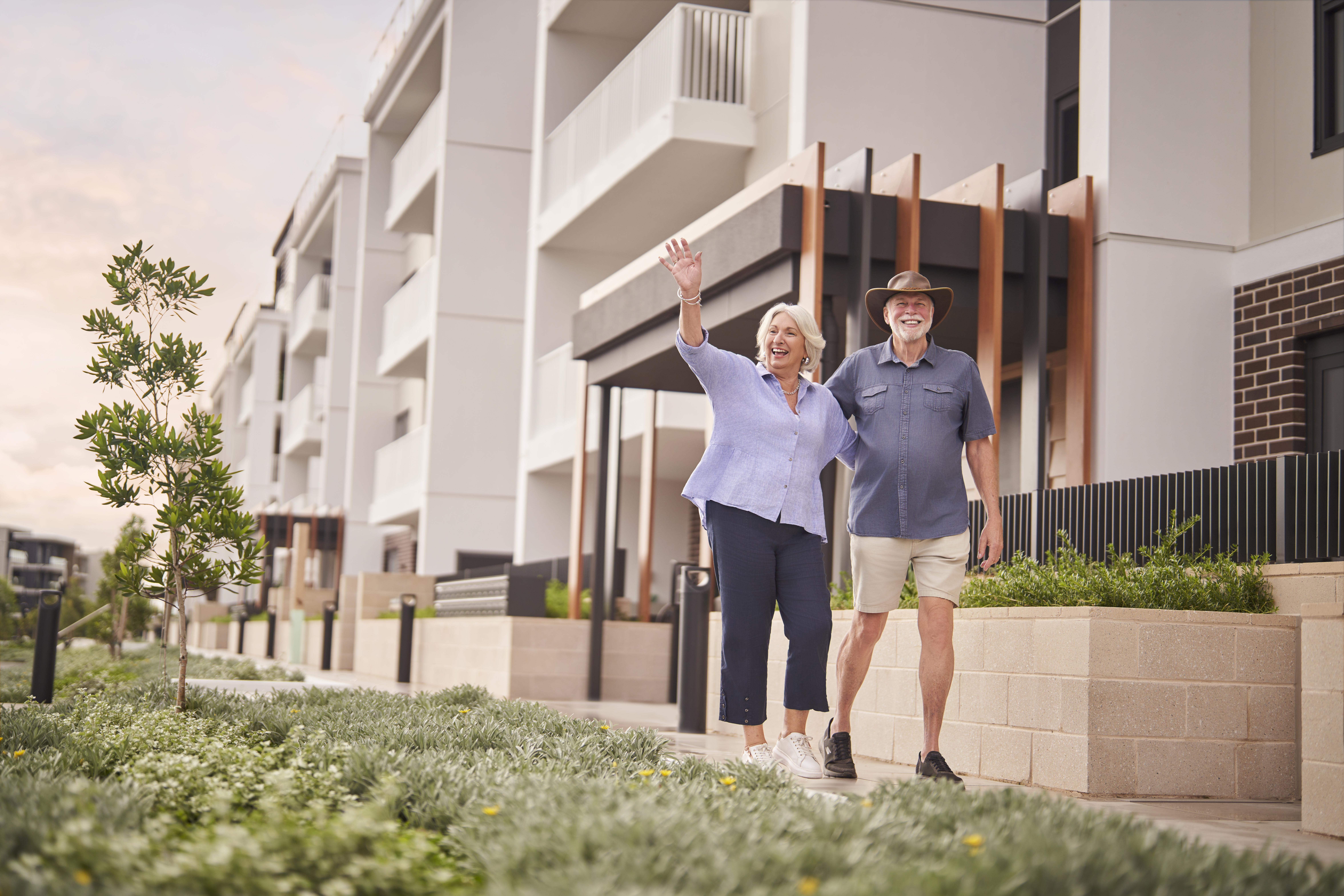 a senior couple walking and waving at someone
