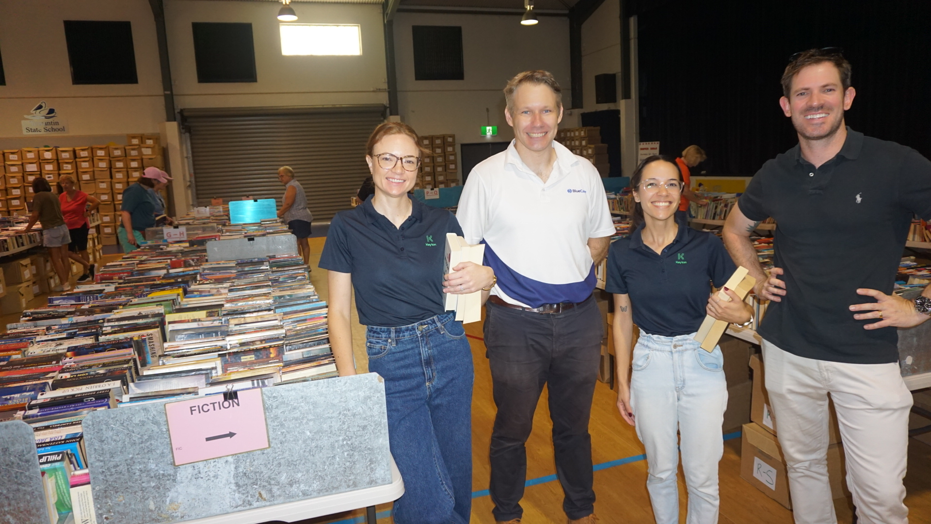 Four people smiling surrounded by boxes of books
