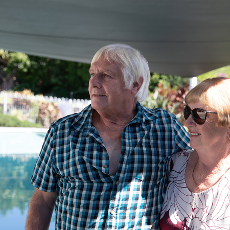 Older man and woman arm in arm while standing next to a pool