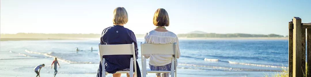 Two woman sitting on chairs looking out to the ocean