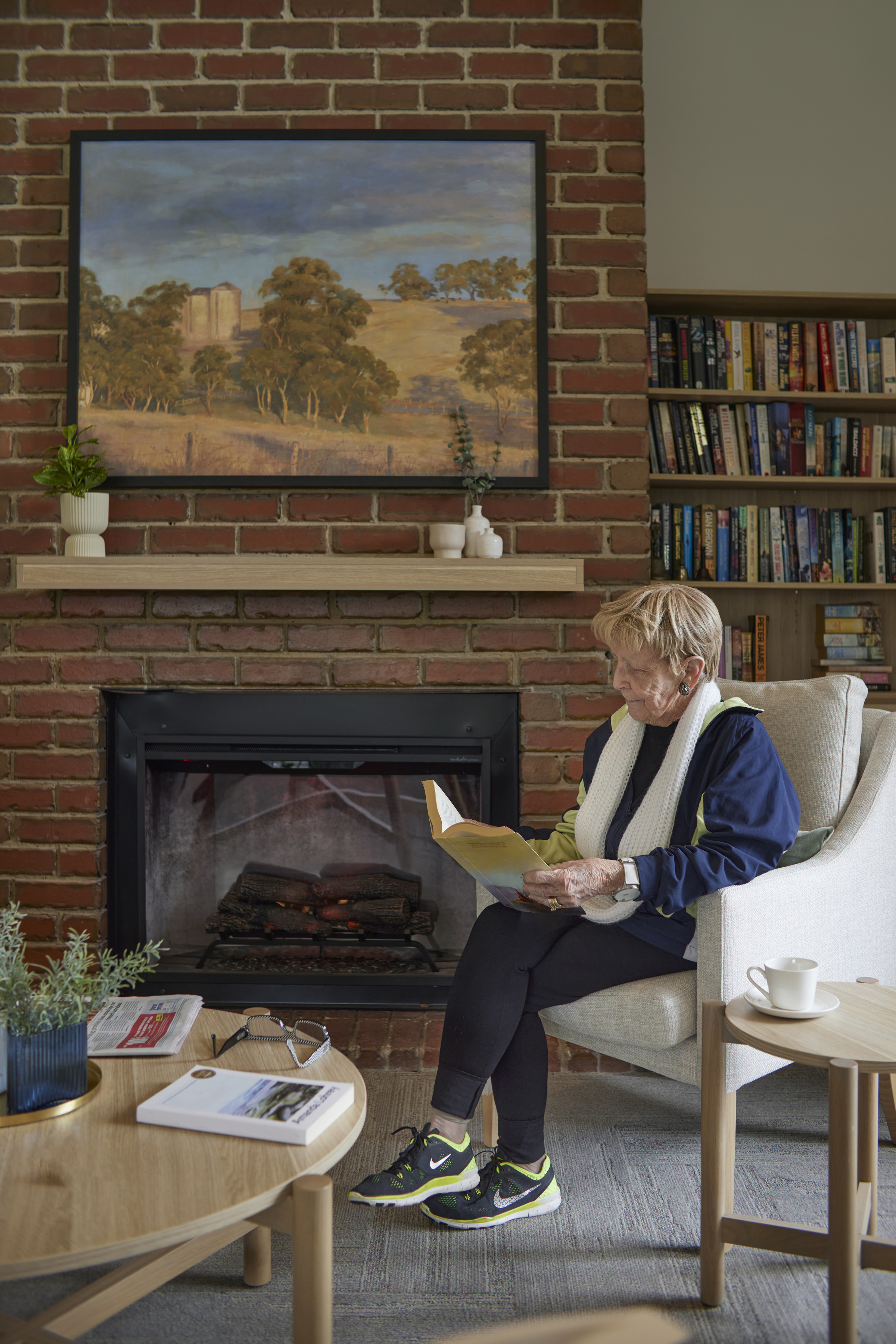 Viewbank Gardens resident reading a book at the fireplace