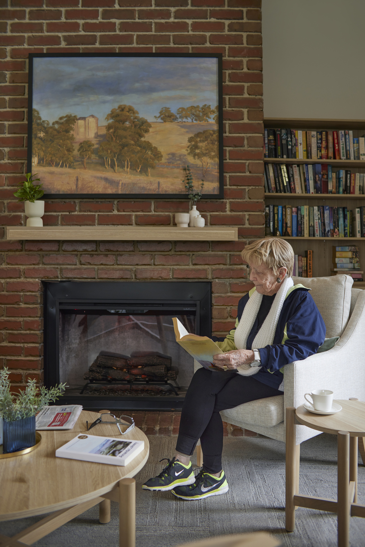 Viewbank Gardens resident reading a book at the fireplace