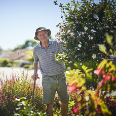 An elderly man wearing a hat standing in his garden in a retirement village