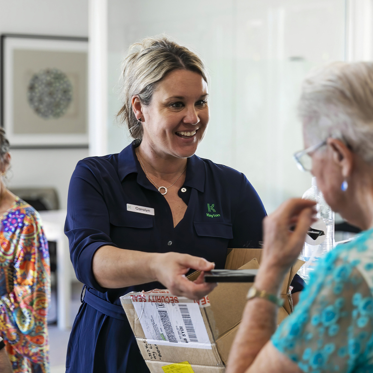 A female Keyton staff member holding a box for an elderly female resident