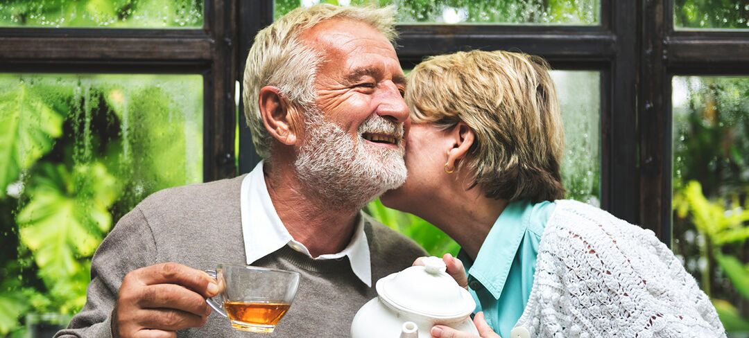 Man and woman sharing tea, the woman kissing the mans cheek
