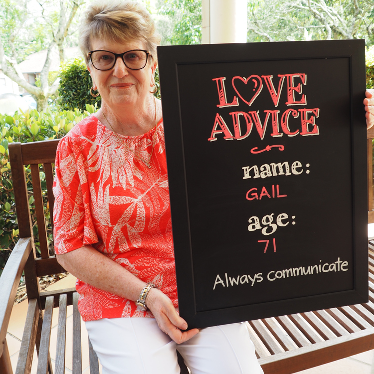 A senior holding a placard with her name, age and a piece of love advice
