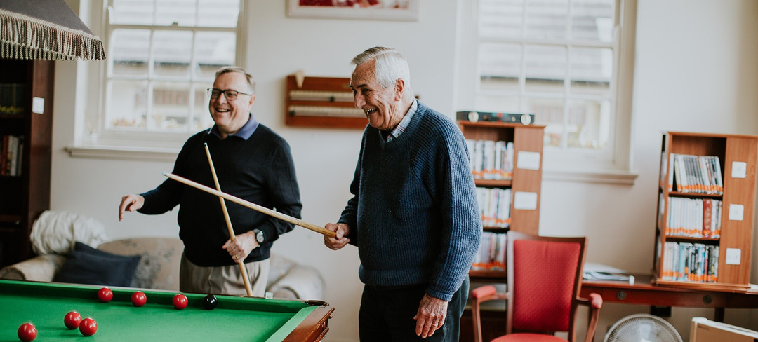 Two elderly gentlemen smiling and playing pool at Annesley Bowral retirement village