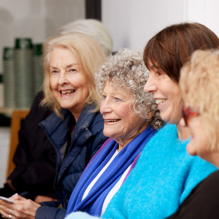 A group of women sitting next to each other and smiling