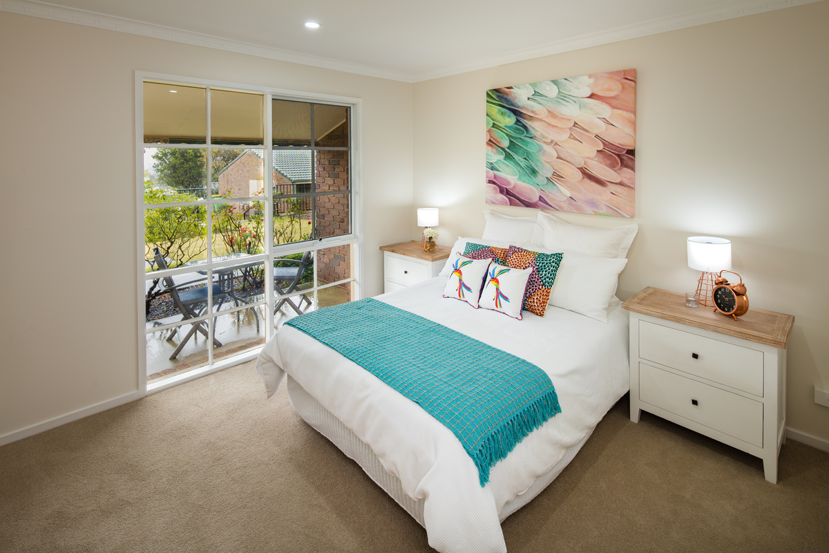 Meadowvale Village bedroom with modern art on wall, bed, bedside table, floor to ceiling window overlooking patio