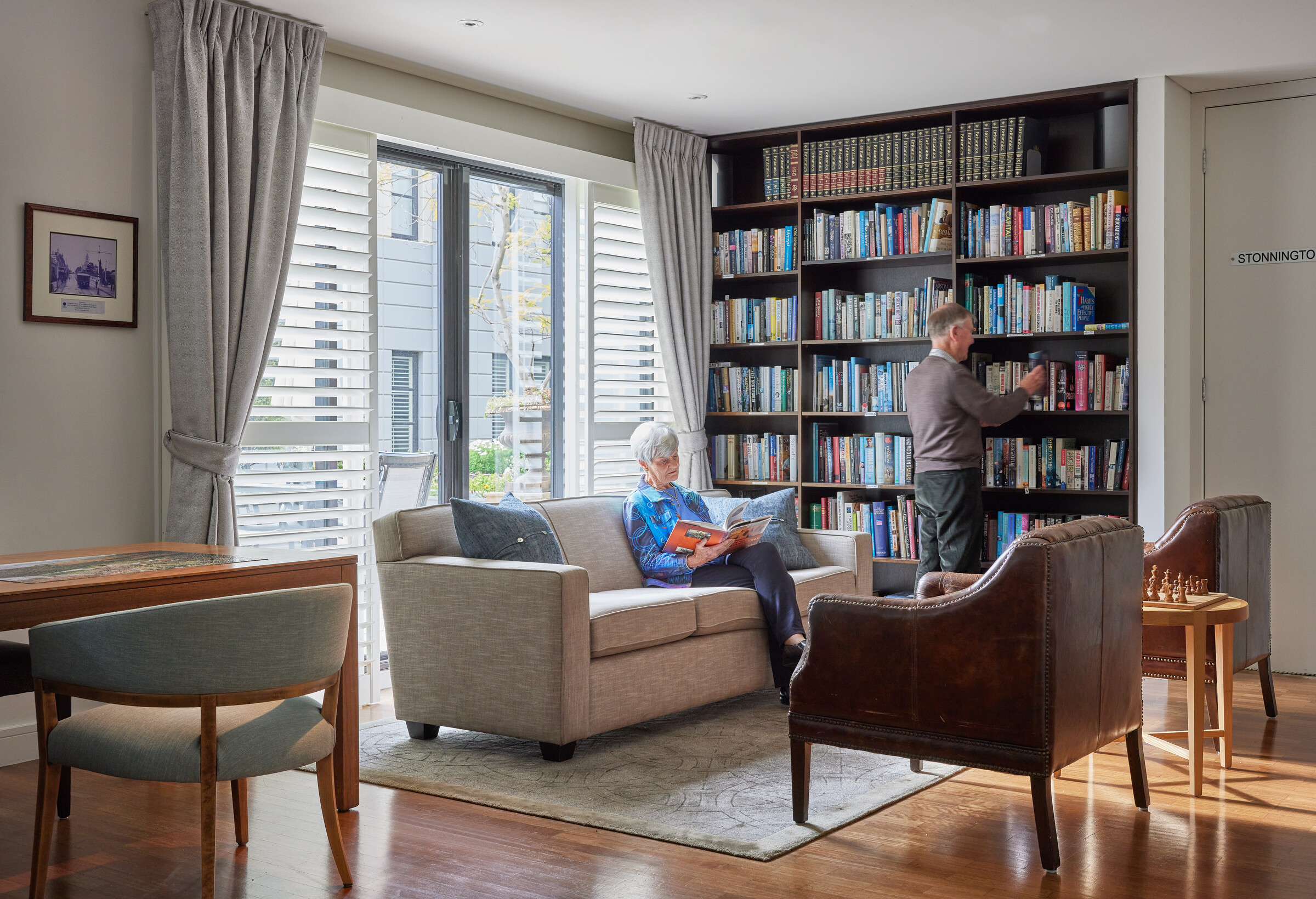 Menzies Malvern couple in library with stocked bookshelves and reading area