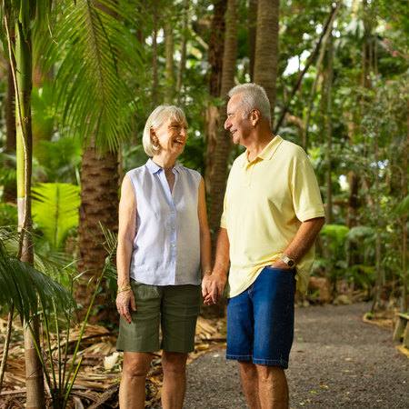 A retired couple holding hands in a lush forest