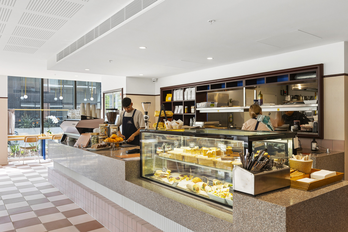 The interior of the cafe showing the display of food and a barista maker making coffee