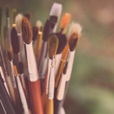 A bundle of paintbrushes sit against a blurred background.