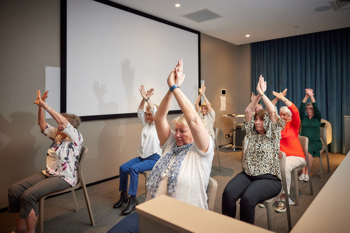 several older women doing a chair yoga class together 
