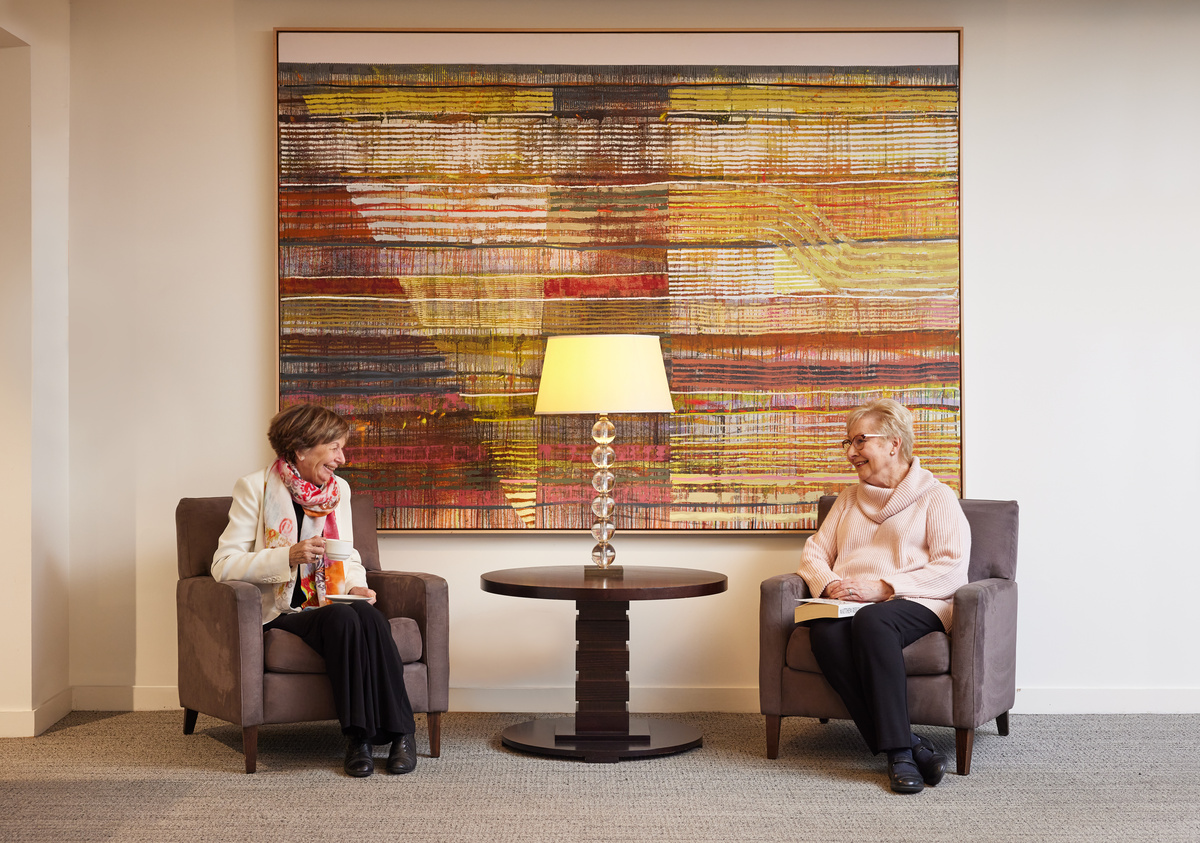 Two ladies sitting in the common area at their apartment retirement village and chatting