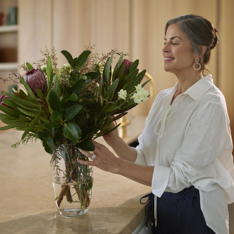 Woman thoughtfully arranges flowers