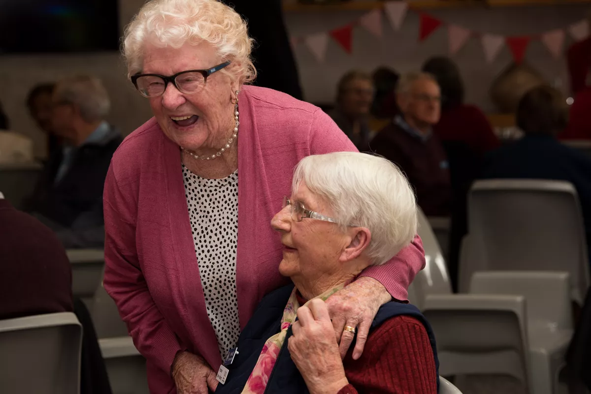 Two female Abervale retirement living residents hugging and laughing