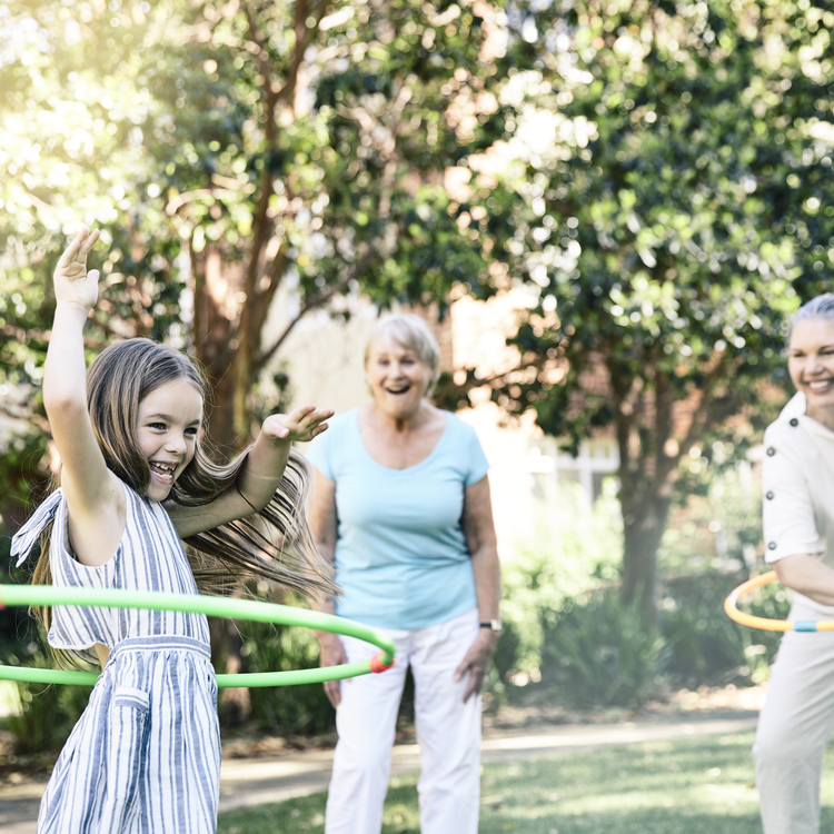 Family having fun playing hula hoop with granddaughter