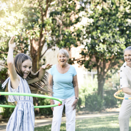 Family having fun playing hula hoop with granddaughter