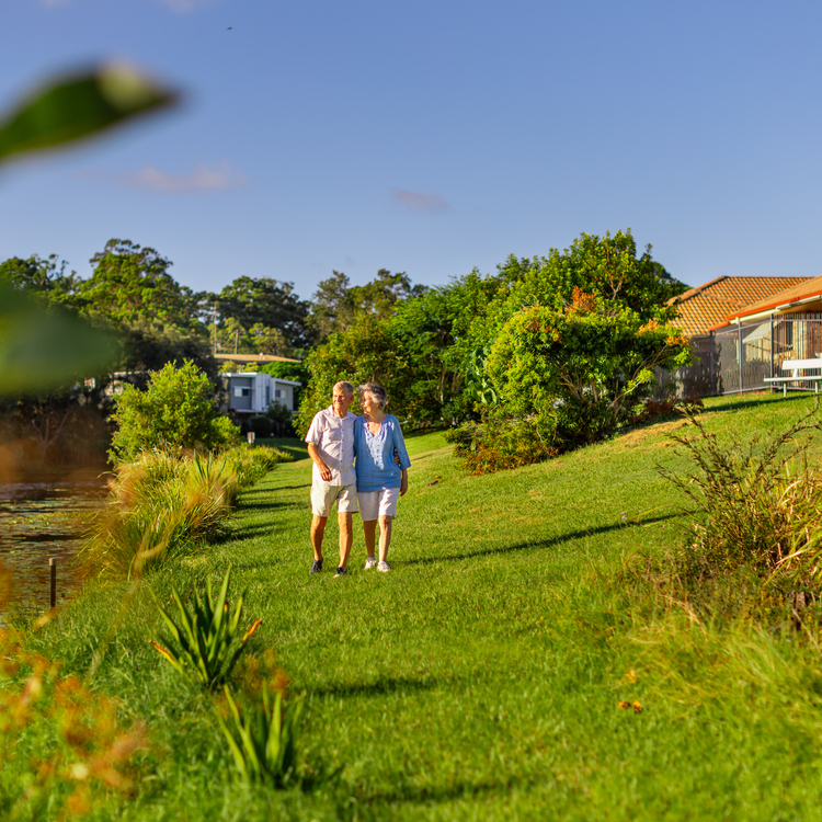 A retired couple walking along gardens at Allora Gardens retirement village