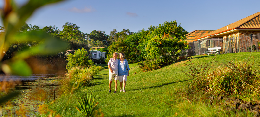 A retired couple walking along gardens at Allora Gardens retirement village