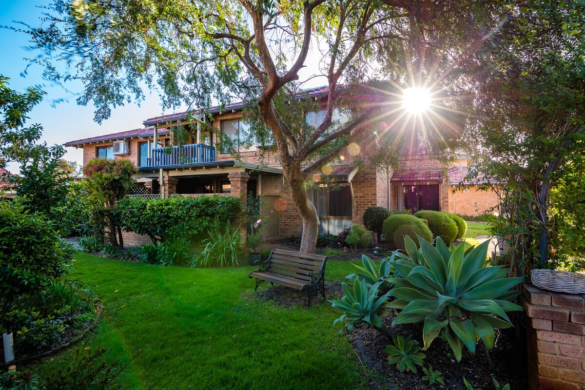 The sun shining through the trees in front of a villa of the Woodlands Park retirement village