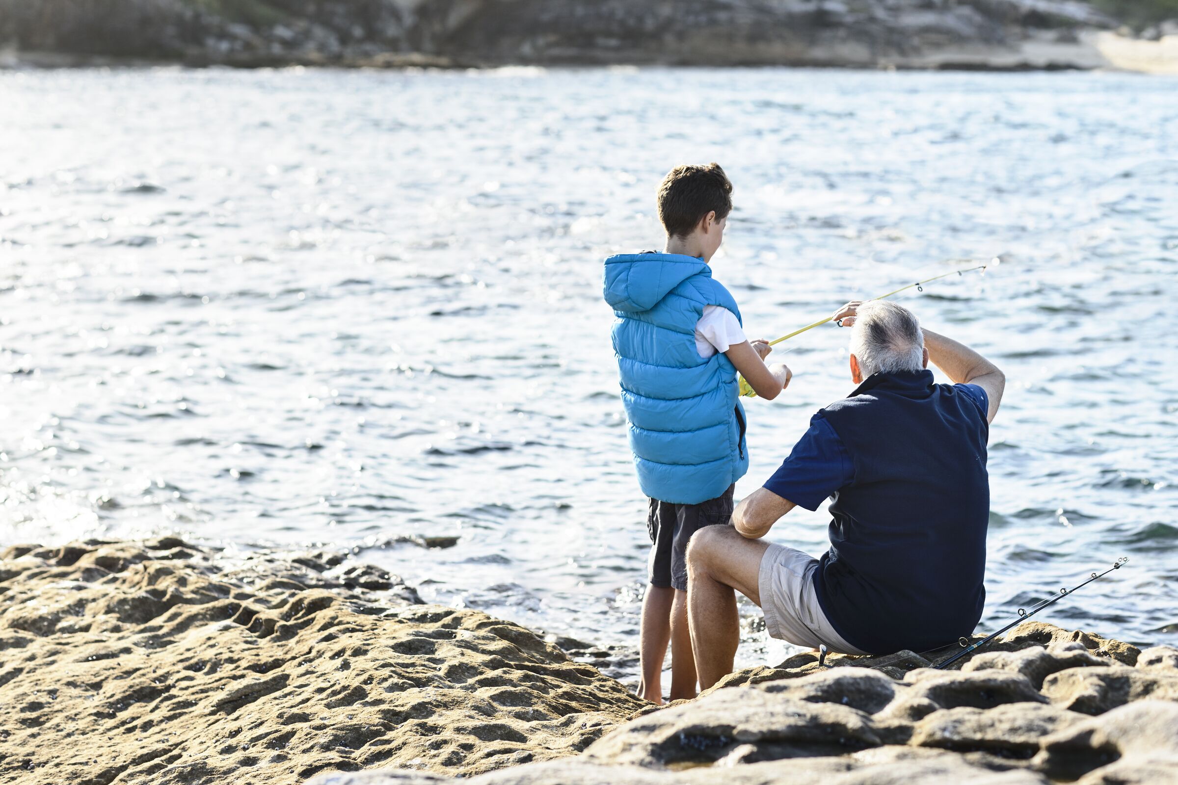 Grandfather and grandson fishing on the side of the beach