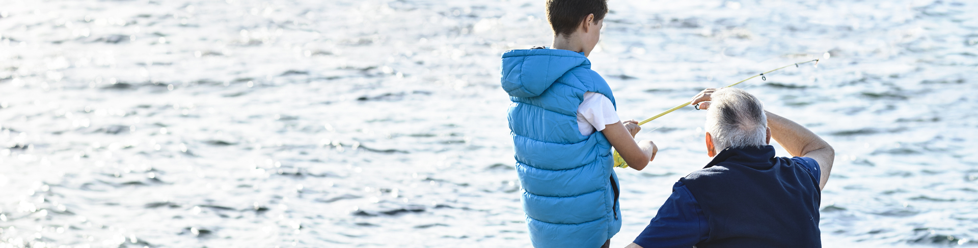 Grandfather and grandson fishing on the side of the beach