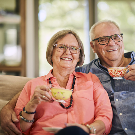 A couple sitting on a couch and having tea together