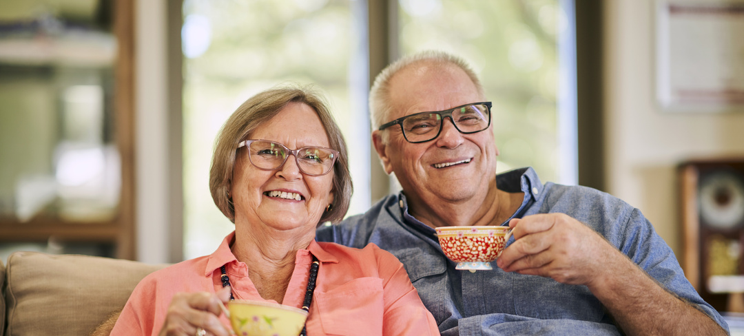 A couple sitting on a couch and having tea together