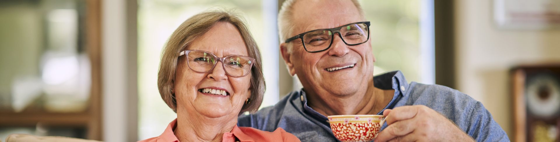 A couple sitting on a couch and having tea together