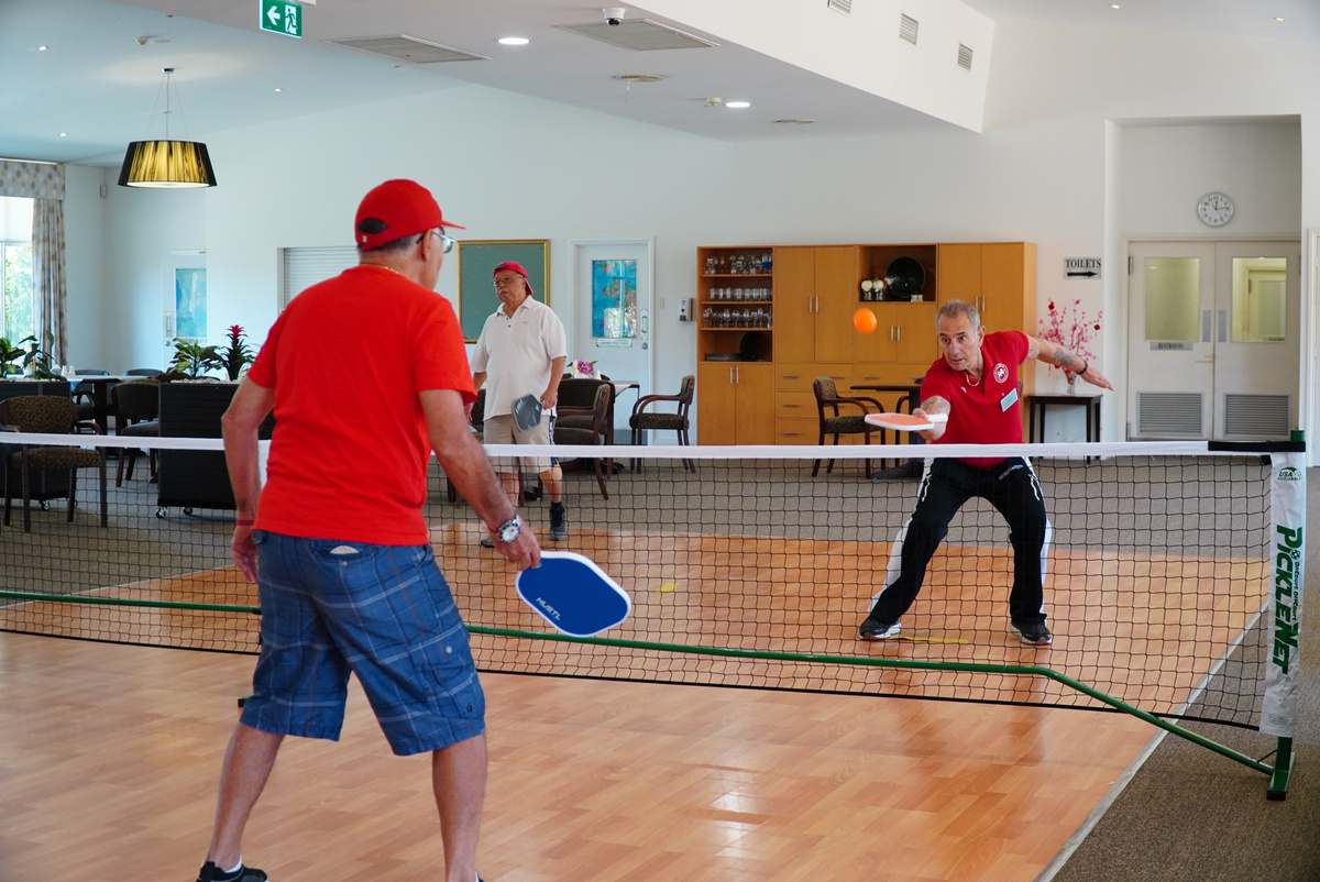 Two seniors playing Pickleball indoors