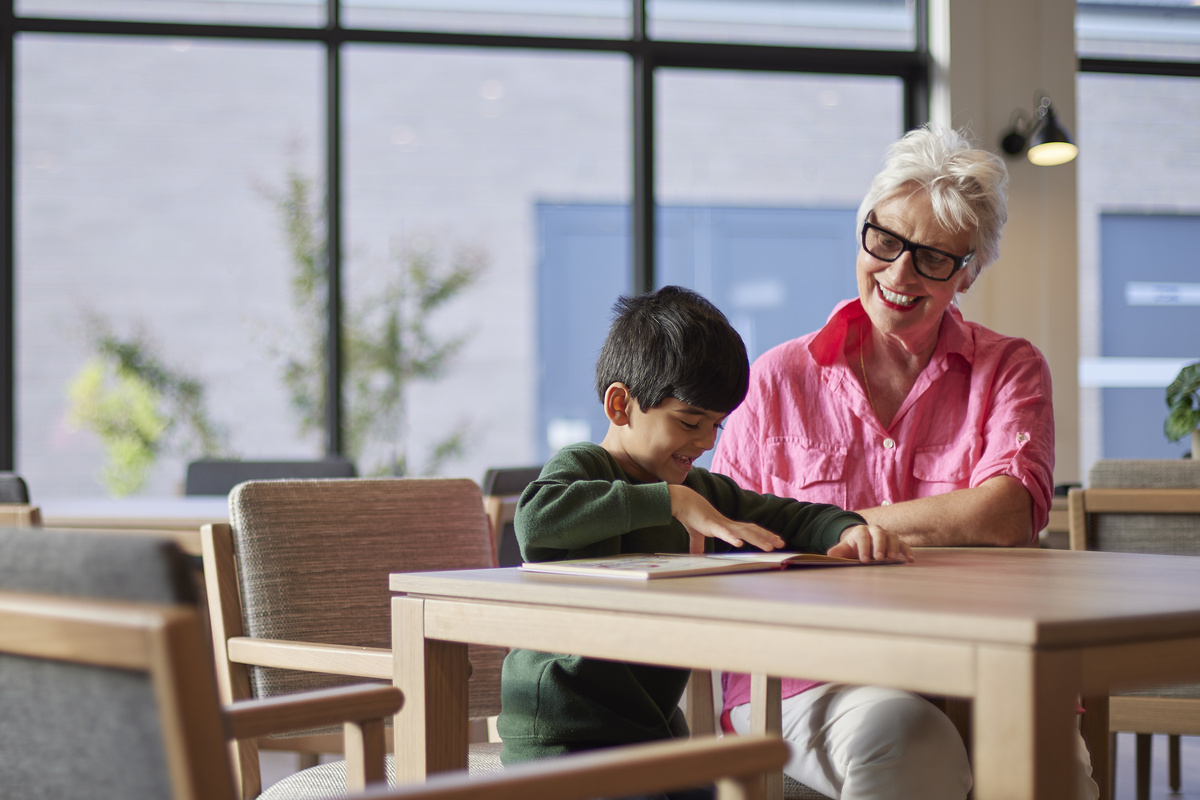 A resident at Sherwin Rise retirement village helps a young boy with his reading.