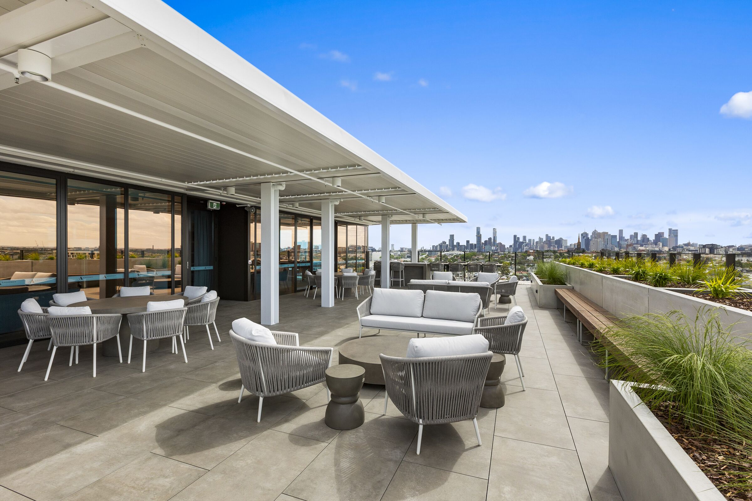 Ardency Kennedy Place apartment terrace with outdoor table and chairs plus seating looking at city views