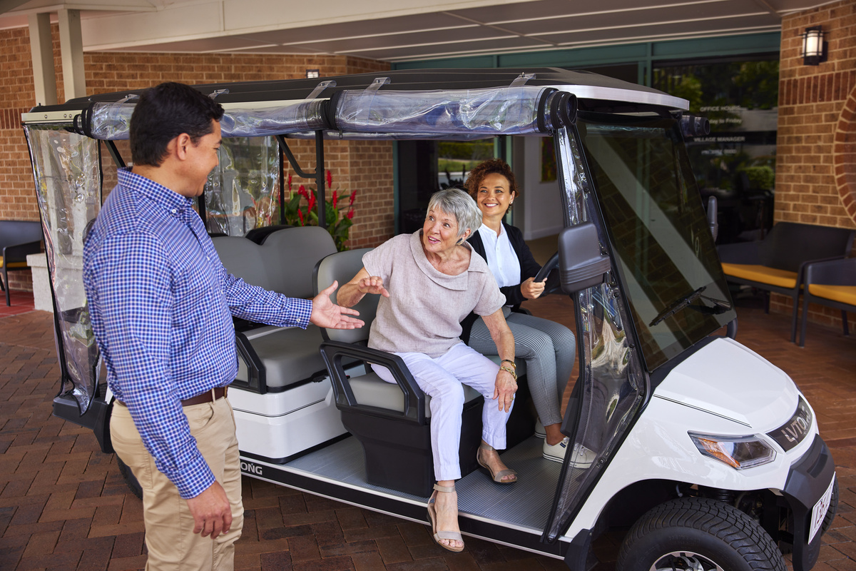 An older woman being helped off a village buggy by a younger man