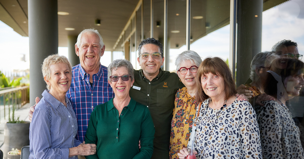 A group of senior residents standing and smiling for the camera