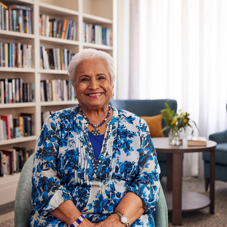 A senior citizen smiling at the camera sitting in a library