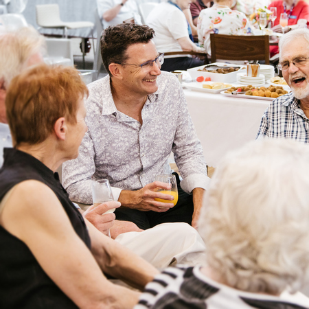 CEO Nathan Cockerill sitting at a table and laughing with retirement living residents