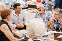 CEO Nathan Cockerill sitting at a table and laughing with retirement living residents