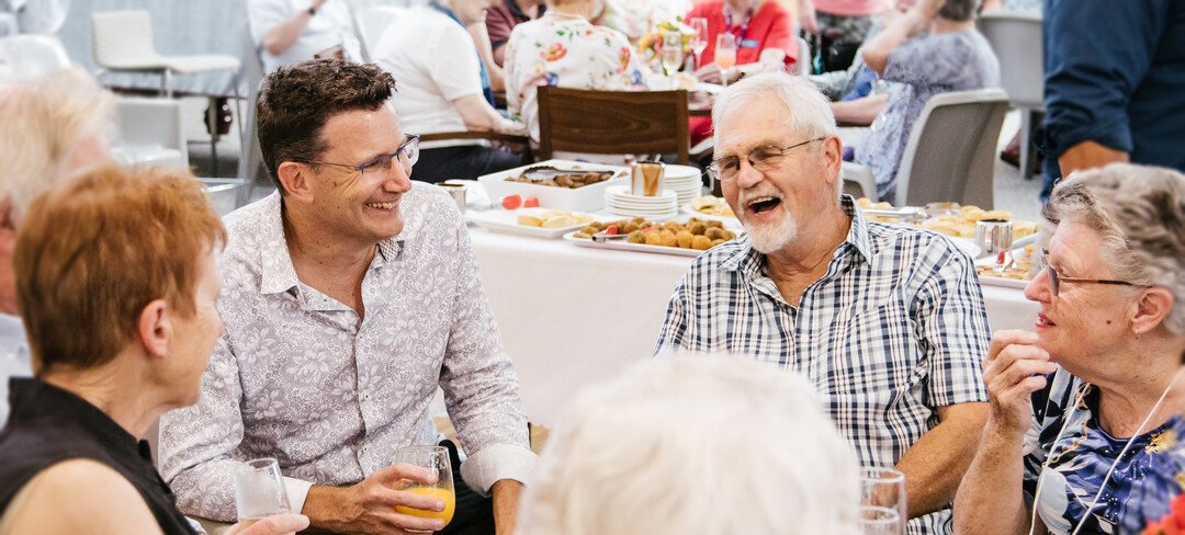 CEO Nathan Cockerill sitting at a table and laughing with retirement living residents
