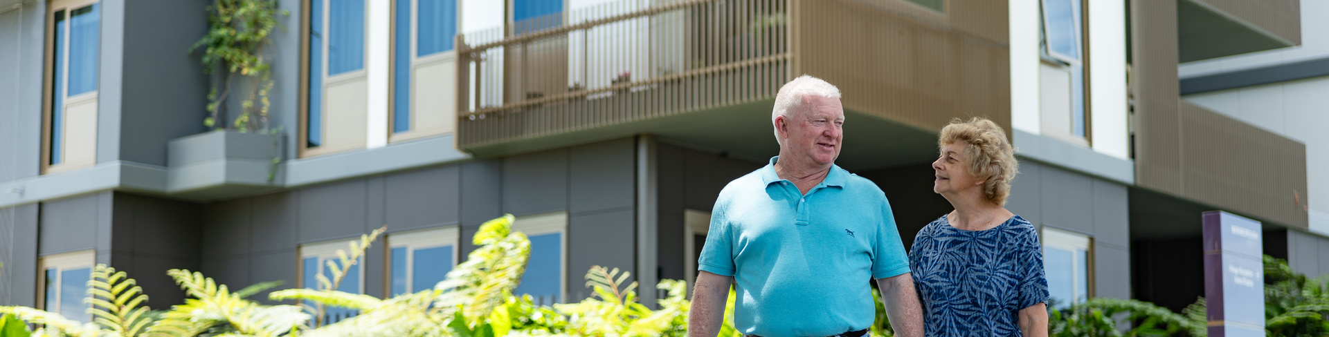 A couple holding hands and walking around an urban retirement village in Brisbane