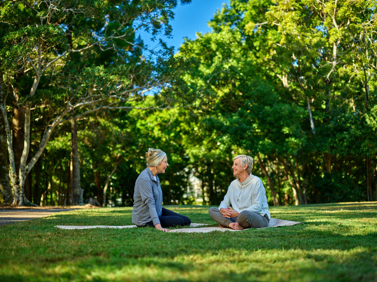 Two ladies chatting whilst doing yoga in the sunshine