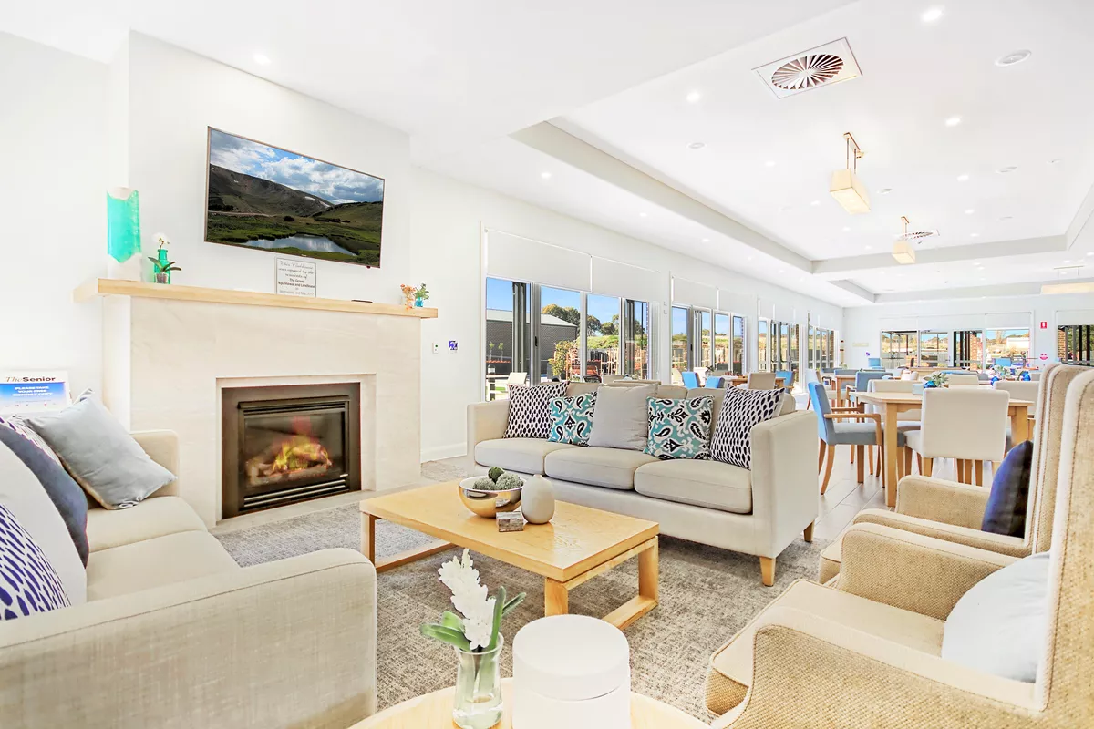 A large community lounge room and dining room with a fireplace at The Grove Ngunnawal retirement village. 