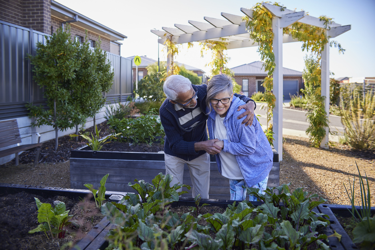 A couple having a laugh in front of vegetable garden patch
