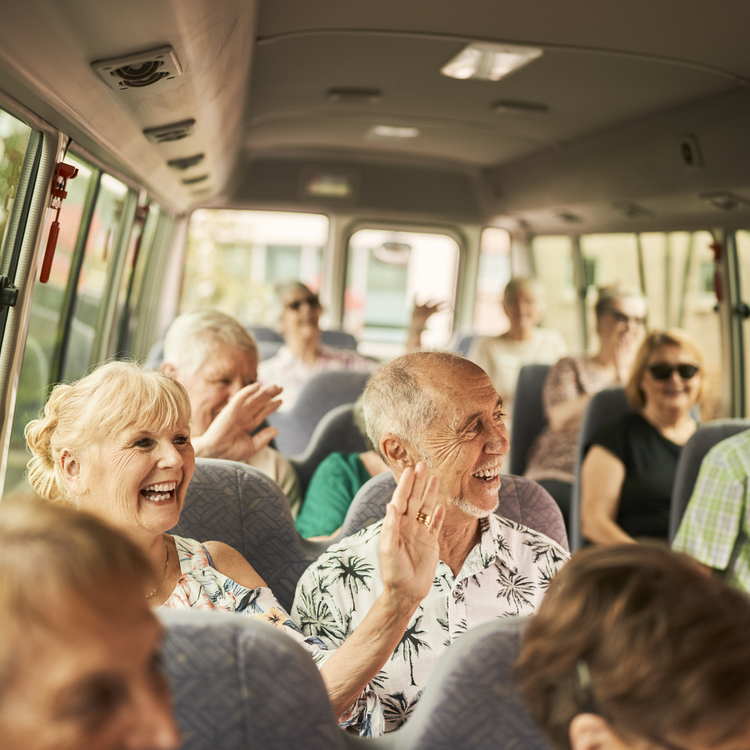 A group of retirees sitting on a bus and smiling